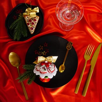 New Year's desserts. Creative table setting with Christmas tree toys. Plates with Christmas toys are placed on a red satin tablecloth.