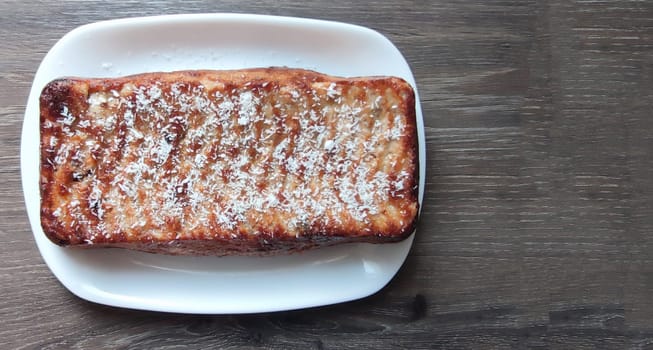 cottage cheese casserole on a white plate on a wooden table, top view, copy space