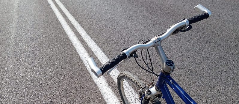 bicycle handlebar and wheel on the background of an asphalt road. High quality photo