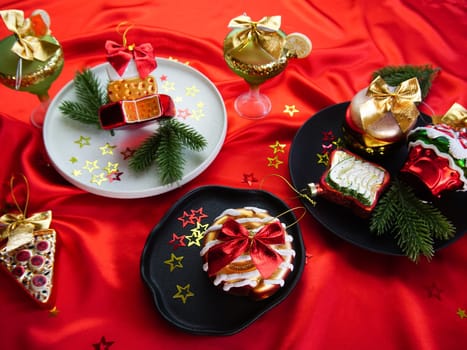 New Year's desserts. Creative table setting with Christmas tree toys. Plates with Christmas toys are placed on a red satin tablecloth.