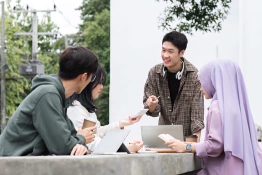 A multiracial group of students at the college, including Muslim and Asian students, sat on benches in a campus break area. Read books or study for exams together..