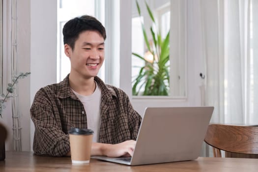 Young businessman uses laptop to do finance, mathematics on wooden table in office and business background, tax, accounting, statistics and analytical research concept..