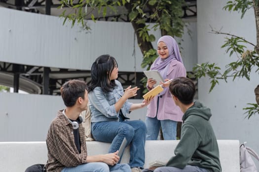 Group of Asian college student reading books and tutoring special class for exam on grass field at outdoors. Happiness and Education learning concept. Back to school concept. Teen and people theme..