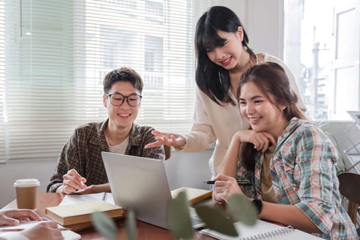 A cheerful and smart Asian woman is standing and sharing his thoughts in a meeting with his team. University students, friendship, startups, teamwork.