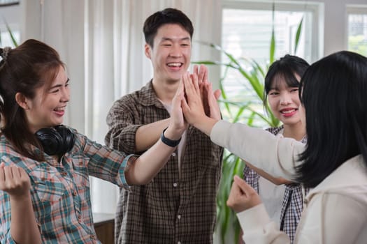 A group of cheerful and happy young Asian friends are gathering together to celebrate the success of a project together in a conference room..