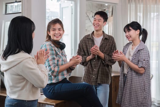 A successful businesswoman sits at a table and is surrounded by congratulating co-workers standing and applauding..