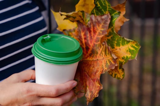 a woman drinks hot coffee from a cup while walking in the city on a sunny autumn day. coffee to take away. Close-up. High quality 4k footage