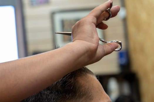 a professional hairdresser cuts a man's hair. visit to the barber shop. hair cutting for the client. creating a hairstyle in a beauty salon. Men's haircut in a barbershop.