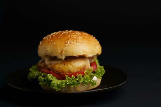 Homemade tasty double burger with beef, salad, bacon, tomatoes and cheese on wooden background. Rustic style.