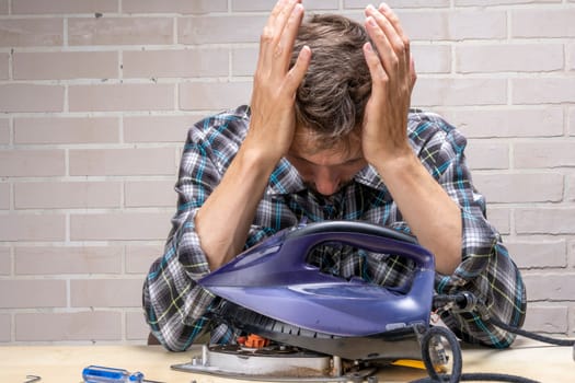 a mountain master repairs an electric iron. the repairman doesn't know how to fix it. Frustrated master. Disassembled electric iron.