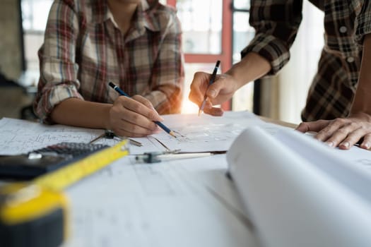 multi ethnic engineer brainstorming and measuring for cost estimating on blueprint and floor plan drawings about design architectural and engineering for houses and buildings.