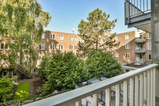 an apartment complex with trees and bushes in the foreground area, as seen from one of the balk's balconys