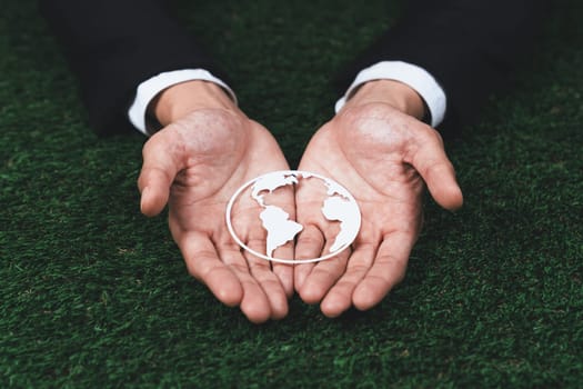 Businessman holding Earth planet icon symbolize eco-friendly business commitment to environmental protection and zero carbon emission. Earth World Day concept to promote eco awareness. Gyre