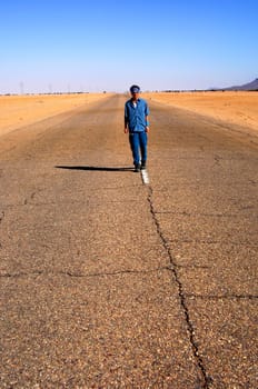 Woman running in the middle of a long straight country road near Al Awaynat,Libya