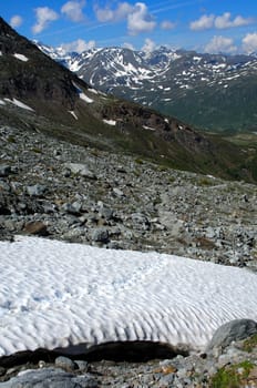 Dangerous snowfield with footprints in the mountains in spring