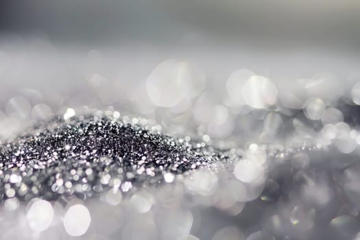 Shimmering silver glitter with soft bokeh effect in a dreamlike scene.