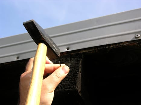 Man hammering a nail into wood with a hammer