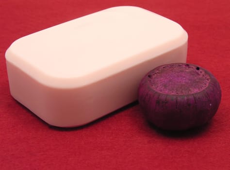Pink soap with decorative items against red background