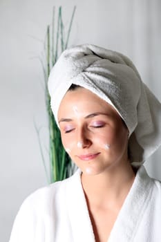 Young woman with cream on face smiling relaxed