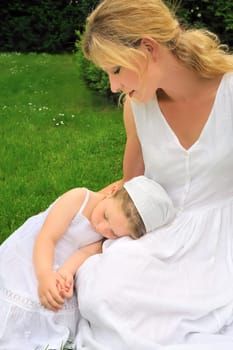 Young mother and daughter resting in meadow