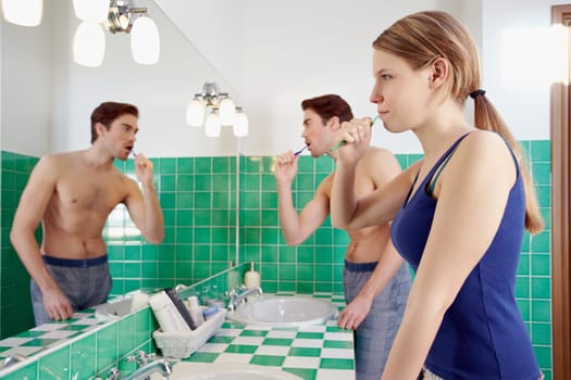 husband and wife brushing teeth in bathr