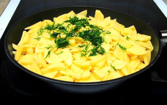 Sliced raw potatoes on frying pan