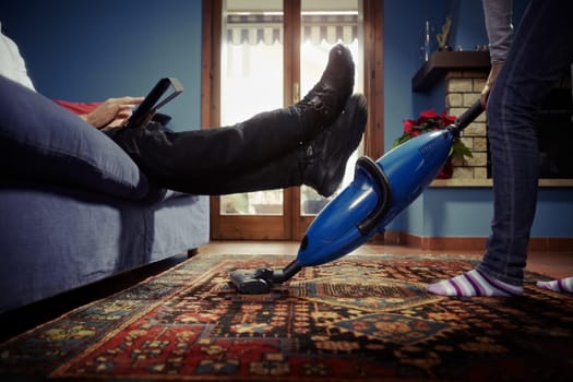 man relaxing while woman doing chores at