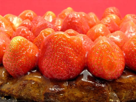 Side close-up of a strawberry cake against a red background