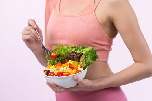 Young sporty Asian woman in sportswear holding salad bowl fill with vibrant of fruit and vegetable. Natural youthful and fit body lifestyle with balance nutrition on isolated background. Vigorous