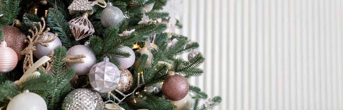 fir branches and decorations in pastel colors, with snow. Elegant Christmas banner from fir branches, beige balls and white stars