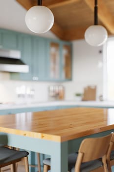 Green kitchen with wood countertops and accent island for product display. Empty kitchen countertop with blurred kitchen background with appliances and utensils. 3D rendering.