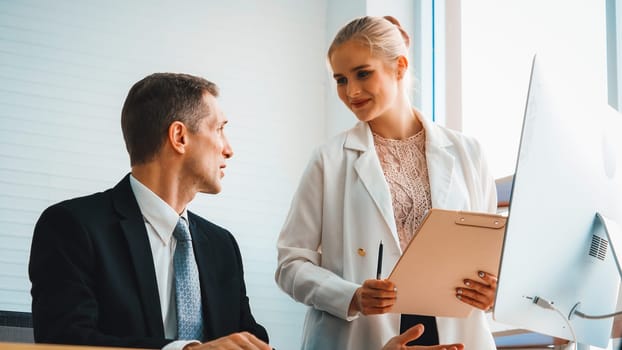 Two business people talk project strategy at office meeting room. Businessman discuss project planning with colleague at modern workplace while having conversation and advice on financial report. Jivy