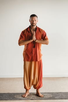 a man in an orange suit does yoga in a fitness room. The concept of health.