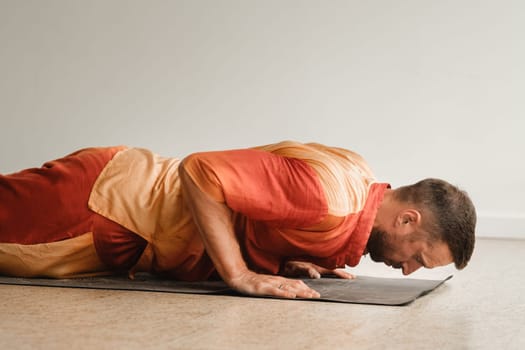 a man in an orange suit does yoga in a fitness room. The concept of health.