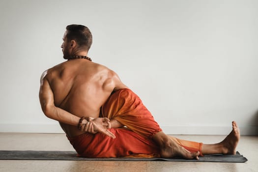 a man with a naked torso does yoga indoors. Fitness Trainer.