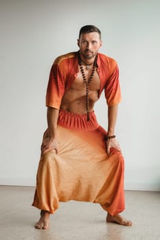 a man in an orange suit does yoga by moving his abdominal muscles in the gym. The concept of health.