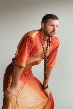 a man in an orange suit does yoga by moving his abdominal muscles in the gym. The concept of health.