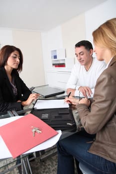 Couple signing property contract with real estate agent