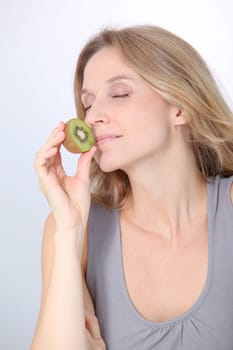 Beautiful blond woman eating kiwis