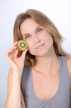Beautiful blond woman eating kiwis