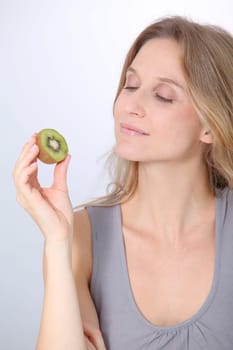 Beautiful blond woman eating kiwis