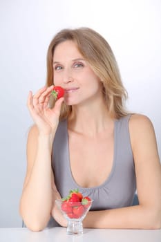 Beautiful blond woman eating strawberries