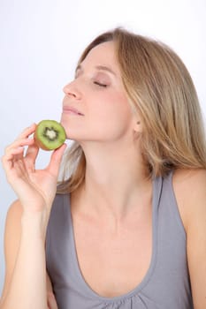 Beautiful blond woman eating kiwis