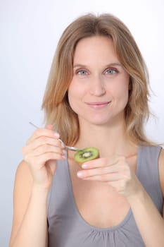 Beautiful blond woman eating kiwis