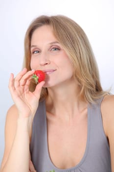 Beautiful blond woman eating strawberries