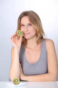 Beautiful blond woman eating kiwis