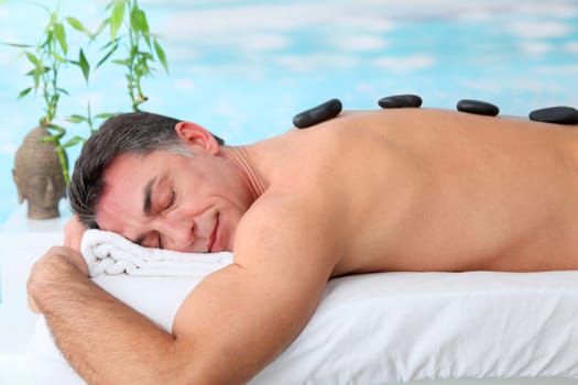 Man laying on massage bed with hot stones