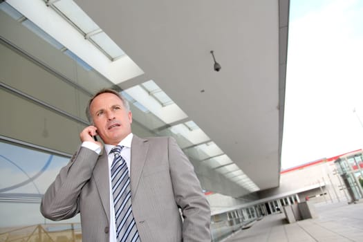Businessman with mobile phone in front of modern building