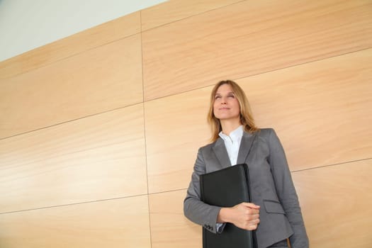 Businesswoman standing in hall against wall