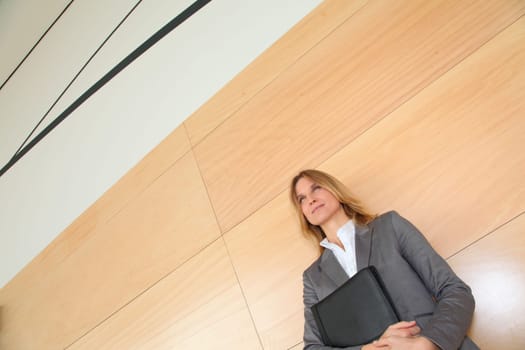 Businesswoman standing in hall against wall